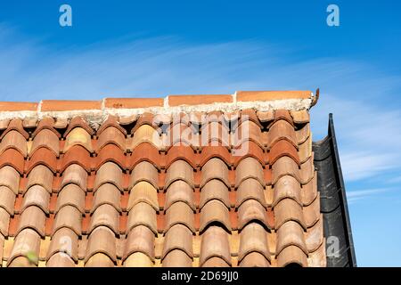 Pantile. Nahaufnahme eines Daches mit Terrakotta-Fliesen (Coppo in italienischer Sprache) und Rinne auf einem blauen Himmel mit Wolken. Venetien, Italien, Europa Stockfoto