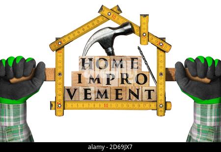 Hände halten ein faltbares Lineal in Form eines Hauses mit Text Home Improvement aus Holzblöcken. Stockfoto