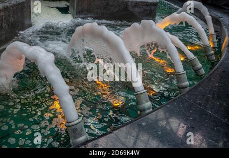 Druckmetalldüsen an einem Innenbrunnen, der Wasserstrahlen sprüht Stockfoto