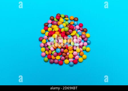 Mehrfarbige runde Bonbons liegen auf einem funkelnden blauen Hintergrund. Festliche Stimmung. Draufsicht Stockfoto