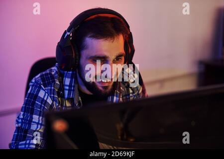 Lächeln während des Prozesses. Portrait von jungen bärtigen Pro Gamer spielen in Online-Videospiel Stockfoto