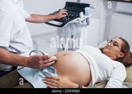 Männliche Arzt tut Ultraschall für eine schwangere Frau in der Krankenhaus Stockfoto