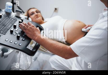 Männliche Arzt tut Ultraschall für eine schwangere Frau in der Krankenhaus Stockfoto