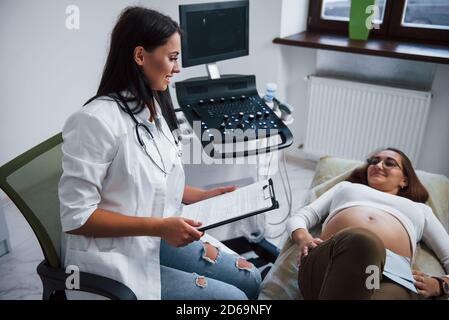 Ärztin spricht über die Ergebnisse von Ultraschall für eine schwangere Frau im Krankenhaus Stockfoto