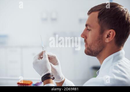 Männlicher Arzt mit Spritze bereitet sich auf die Blutentnahme vor Im Klinikraum Stockfoto