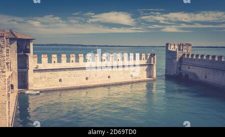 Sirmione, Italien, 11. September 2019: Kleiner befestigter Hafen mit türkisfarbenem Wasser, Scaligero Burg Castello Festung, Stadt am Gardasee, mittelalterliche Burg mit Steintürmen und Backsteinmauern, Lombardei Stockfoto