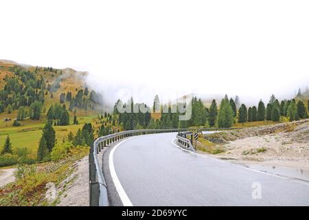 Blick auf eine Bergstraße hoch in den Alpen in Italien. Nasser nebliger Morgen. Rutschige Straße. Temperaturabfall Stockfoto
