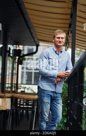 Vorderansicht von Kerl in Jeans, die in der steht Cafe tagsüber Stockfoto