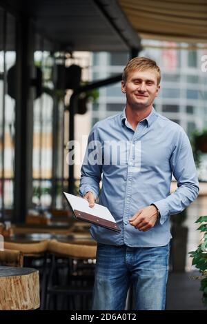 Vorderansicht von Kerl in Jeans, die in der steht Cafe tagsüber Stockfoto