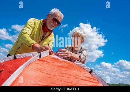 Seniorenpaar bereitet sich auf die Erholung vor, legt ein Zelt auf Stockfoto