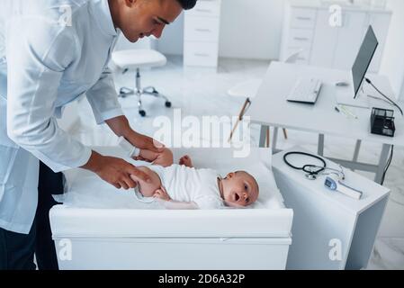 Junge Kinderarzt ist mit kleinen Baby in der Klinik an Tagsüber Stockfoto