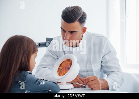 Prozess der Prüfung Vision. Junge Augenärztin ist mit wenig weiblichen Besucher in der Klinik Stockfoto