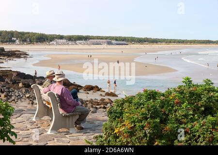 Männer sitzen und reden auf einer Bank mit Blick auf den Strand entlang marginal Way in Ogunquit, Maine, USA. Stockfoto