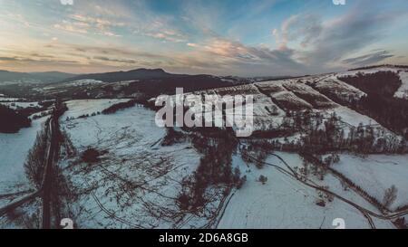 Untere Beskid, Karpaten Bergkette im Winter Luftbild, orange und rosa Himmel Stockfoto