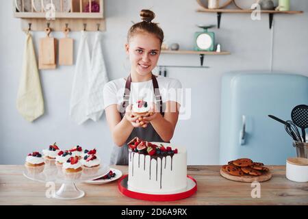 Frau steht drinnen in der Küche mit hausgemachtem Kuchen Stockfoto