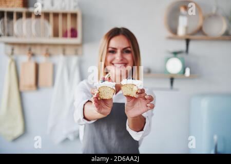 Frau steht drinnen in der Küche mit hausgemachtem Kuchen Stockfoto