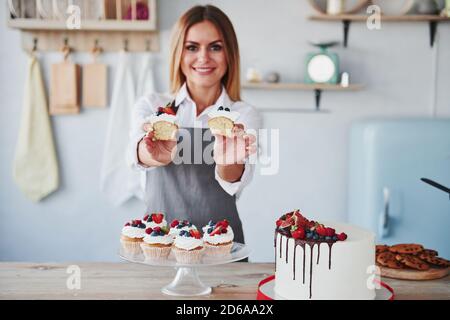 Frau steht drinnen in der Küche mit hausgemachtem Kuchen Stockfoto