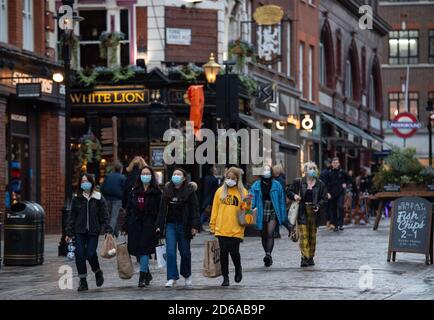 Menschen mit Gesichtsmasken in Covent Garden, im Zentrum von London, nachdem der Bürgermeister von London Sadiq Khan angekündigt hat, dass London ab Mitternacht am Freitag auf Tier-2-Coronavirus-Beschränkungen umgestellt wird. Stockfoto