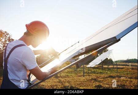 Verwenden Sie einen Akkuschrauber. Männlicher Arbeiter in blauer Uniform im Freien mit Solarbatterien an sonnigen Tagen Stockfoto