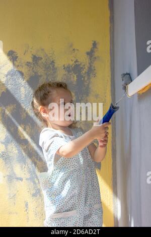 Kleines Mädchen malt die Wand mit Farbrolle. Stockfoto