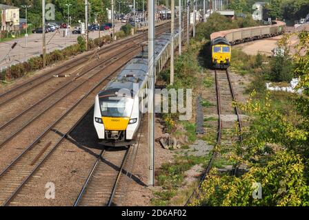 Klasse 700 EMU passiert einen Diesel der Klasse 66 mit Zuschlagstoffzug in der Werft in Hitchin, Hertfordshire Stockfoto