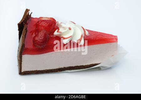 Scheibe Erdbeerkäsekuchen mit Gelee und Erdbeeren. Gelee und Käsekuchen auf einer Butterbrotschokolade-Basis. Cremiges Dessert mit Beeren und Choc Stockfoto