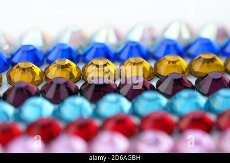 Farbige Acryl-Glitzersteinchen Nahaufnahme. Dekorative Steine zum Dekorieren von Taschen, Kleidung in blau, rot, gelb. Bunte Kunststoff facettierte Steine Stockfoto