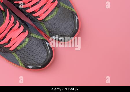 Graue Sneakers mit rosa Schnürsenkeln Draufsicht. Damen Sportschuhe auf rosa Hintergrund. Gesundes Lifestyle-Konzept. Stockfoto