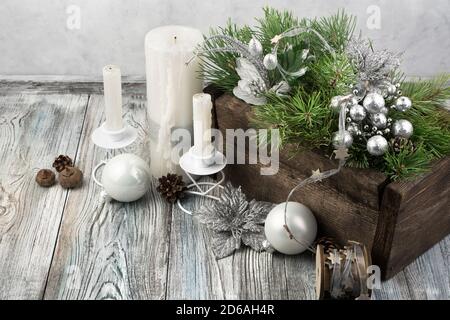 Schöne Kerzen und verzierte Kiefernnetze in einer Holzkiste auf einem grauen Vintage Hintergrund. Stockfoto