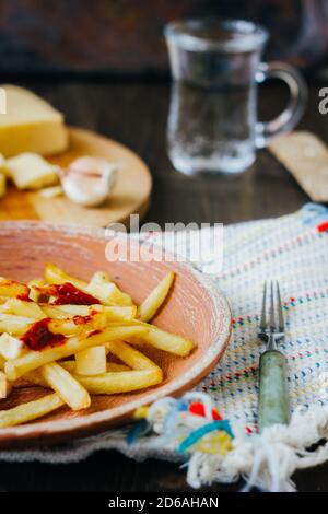 Pommes frites auf schwarzer Oberfläche anprittieren. Kanadisches Gericht mit Kartoffeln, Käse und Sauce Stockfoto
