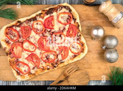 Hausgemachte Kuchen mit Käse, Speck und Tomaten auf einem weihnachtlichen Hintergrund. Stockfoto