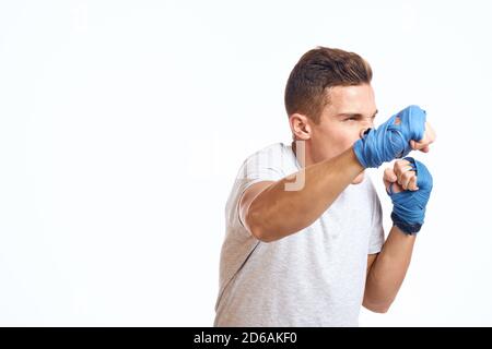 Sportliche Boxer in blauen Handschuhen üben Schläge auf ein Beschnittene Ansicht mit hellem Hintergrund Stockfoto