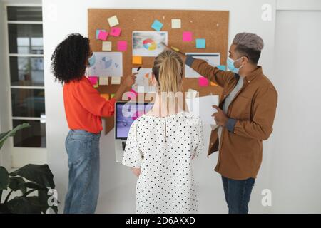 Bürokollegen mit Gesichtsmaske diskutieren über Memonotizen bei Büro Stockfoto