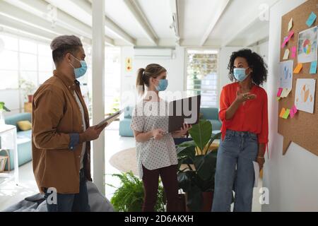 Bürokollegen tragen Gesichtsmasken und diskutieren über Memonotizen bei Büro Stockfoto