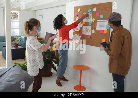 Bürokollegen mit Gesichtsmaske diskutieren über Memonotizen bei Büro Stockfoto
