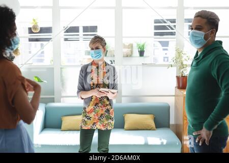 Bürokollegen mit Gesichtsmaske sprechen im Büro Stockfoto