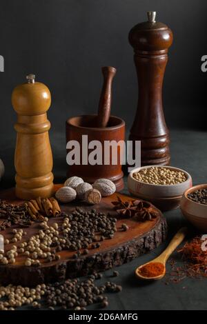 Stillleben mit verschiedenen Gewürzen wie Pfeffer, Muskatnuss, Zimt und Paprika auf schwarzem Hintergrund. Stockfoto