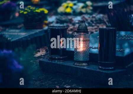 Brennende Kerzen, bunte Blumen und festliche Dekorationen auf Gräbern auf dem Friedhof Stockfoto