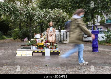 Berlin, Deutschland. Oktober 2020. Eine Fußgängerin geht an einer Komforts-Frauenstatue in Berlin, der Hauptstadt Deutschlands, vorbei, 15. Oktober 2020. Eine Statue, die gerade von einem deutschen Verein für koreanische Geschichte, dem Korea-Verband, Ende September in Berlin errichtet wurde, soll vorerst verbleiben, teilte das zuständige Bezirksamt kürzlich mit. Quelle: Xinhua/Alamy Live News Stockfoto