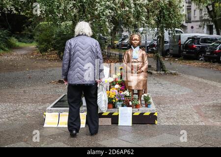 Berlin, Deutschland. Oktober 2020. Eine Fußgängerin blickt auf eine Komforts-Frauenstatue in Berlin, der Hauptstadt Deutschlands, 15. Oktober 2020. Eine Statue, die gerade von einem deutschen Verein für koreanische Geschichte, dem Korea-Verband, Ende September in Berlin errichtet wurde, soll vorerst verbleiben, teilte das zuständige Bezirksamt kürzlich mit. Quelle: Xinhua/Alamy Live News Stockfoto