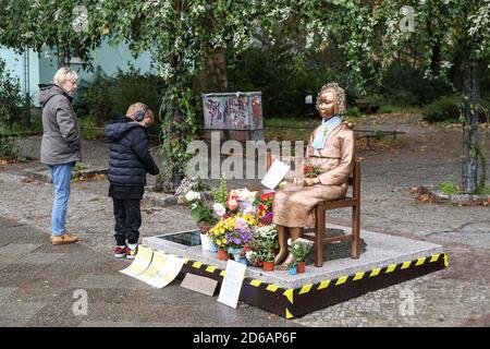 Berlin, Deutschland. Oktober 2020. Fußgänger schauen sich eine Komfortfrauenstatue in Berlin an, Hauptstadt Deutschlands, 15. Oktober 2020. Eine Statue, die gerade von einem deutschen Verein für koreanische Geschichte, dem Korea-Verband, Ende September in Berlin errichtet wurde, soll vorerst verbleiben, teilte das zuständige Bezirksamt kürzlich mit. Quelle: Xinhua/Alamy Live News Stockfoto