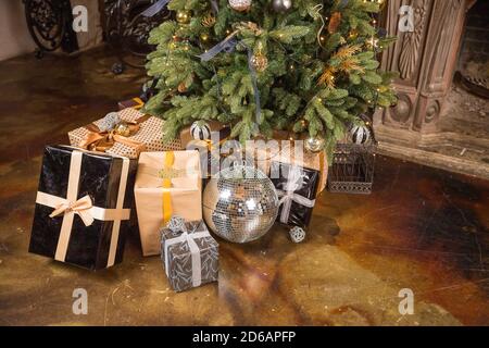 Weihnachtsgeschenkboxen unter der Tanne. Handwerk, Gold und schwarze Farben von Bändern und Papier.Neujahrsgeschenke. Weihnachtsfeiertagskonzept. Gemütliches Zuhause Stockfoto