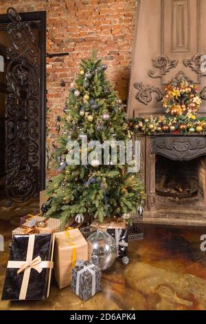 Weihnachtsgeschenkboxen unter der Tanne. Handwerk, Gold und schwarze Farben von Bändern und Papier.Neujahrsgeschenke. Weihnachtsfeiertagskonzept. Gemütliches Zuhause Stockfoto