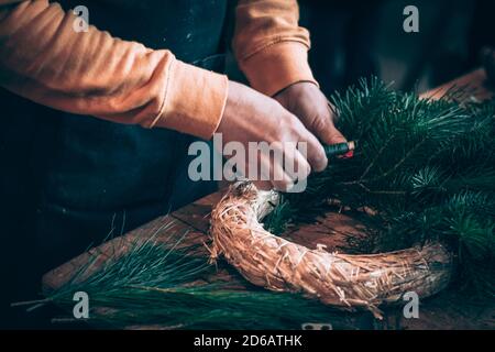 Stroh runden Basis, Scheren und grünen Zweigen Komponenten in menschlichen Händen in Aktion Stockfoto