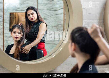 Portrait einer weiblichen Friseur stehen und machen Frisur von einer niedlichen schönen jungen Frau in Schönheitssalon, Schönheitssalon Konzept. Stockfoto