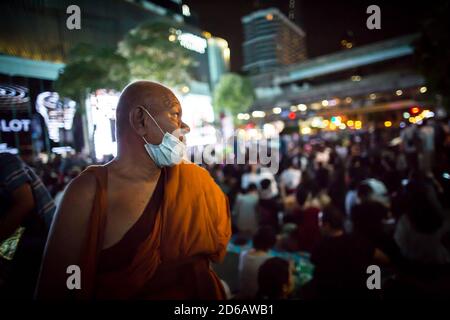 Bangkok, Thailand. Oktober 2020. Ein thailändischer buddhistischer Mönch sah während einer regierungsfeindlichen Demonstration prodemokratische Demonstranten betrachten. Tausende von prodemokratischen Demonstranten gingen auf die Straße an der Kreuzung Ratchaprasong, dem geschäftigsten Sektor Bangkoks, und forderten den Rücktritt des thailändischen Premierministers. Premierminister Prayut Chan-o-cha hat den Ausnahmezustand erklärt und Versammlungen von mehr als fünf Personen nach dem Protest vom 14. Oktober 2020 verboten. Kredit: SOPA Images Limited/Alamy Live Nachrichten Stockfoto