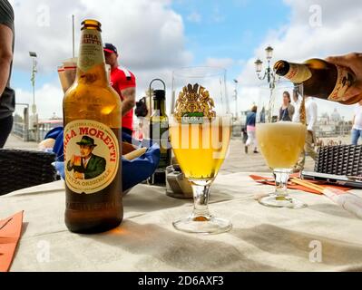 Eine weibliche Hand gießt ein italienisches Bier in ein Glas aus einer Flasche in einem Straßencafé am Canale Grande in Venedig, Italien Stockfoto