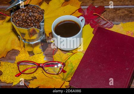 Heißer Kaffee in roter Tasse mit Dampf und Brillen auf gestapelten Büchern Holzhintergrund, Kaffeepause Konzept Stockfoto