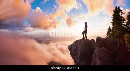 Abenteuerliche weibliche Wanderin auf einem Berg mit Wolken Stockfoto