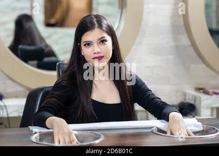 Hübsches junges indisches Mädchen sitzt in einem Salon für Maniküre, Beauty-Salon-Konzept, Schönheit und Gesundheitswesen Konzept. Stockfoto